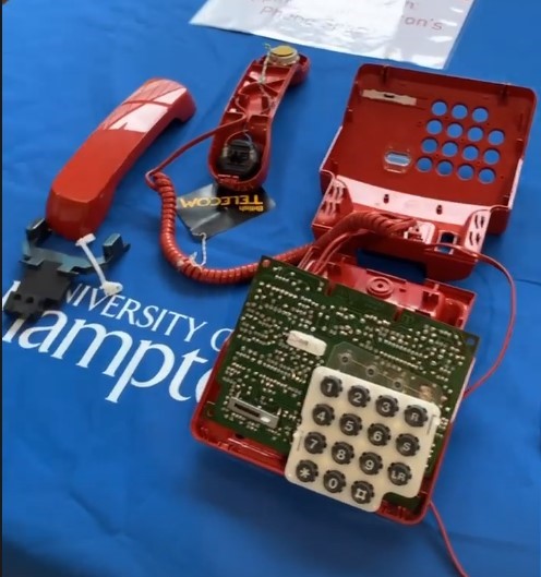 Image shows a disassembled red telephone on a blue Southampton university-branded tablecloth.