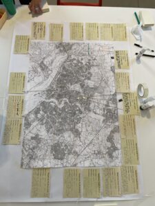 An A1 map of Southampton (black and white) is set out on a table and surrounded by arts supplies, mobile phones, and a set of 'archive tags' on which people can write their memories. Each tag has 'Telephonic Youth Archive' printed on it.