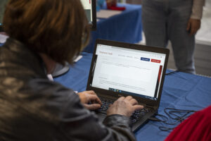 Image of a white woman with medium length brown hair using a laptop to visit telephonicyouth.co.uk.